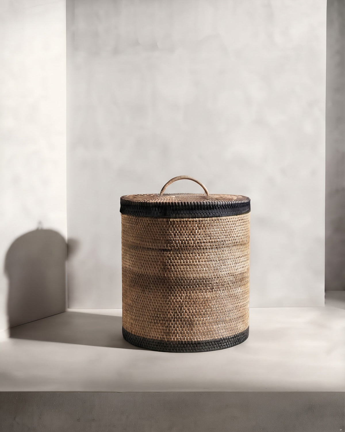 Hand‑woven rattan waste paper basket with fitted lid and dark olive detailing | Anboise