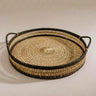 A round woven rattan tray with two side handles, featuring a natural rattan center and olive woven borders | Anboise