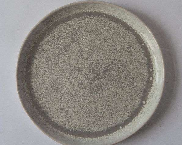 A round stoneware dinner plate with a gray reactive glaze.