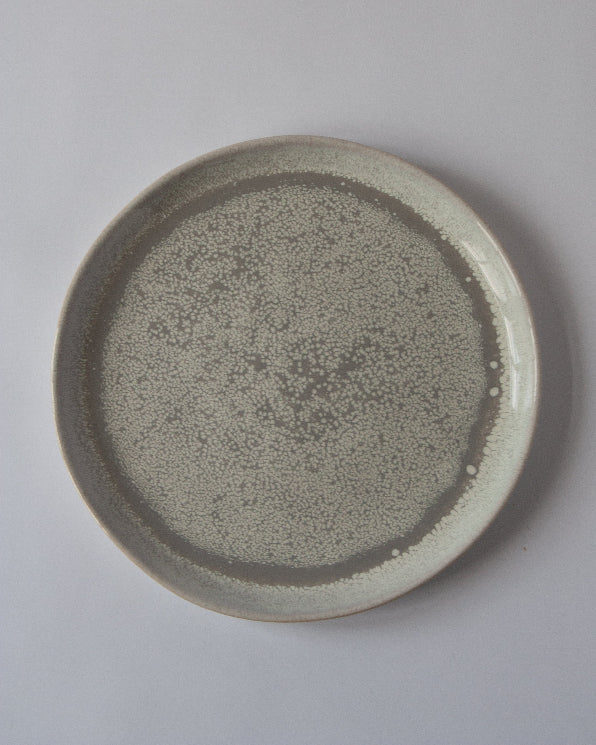 A round stoneware dinner plate with a gray reactive glaze.