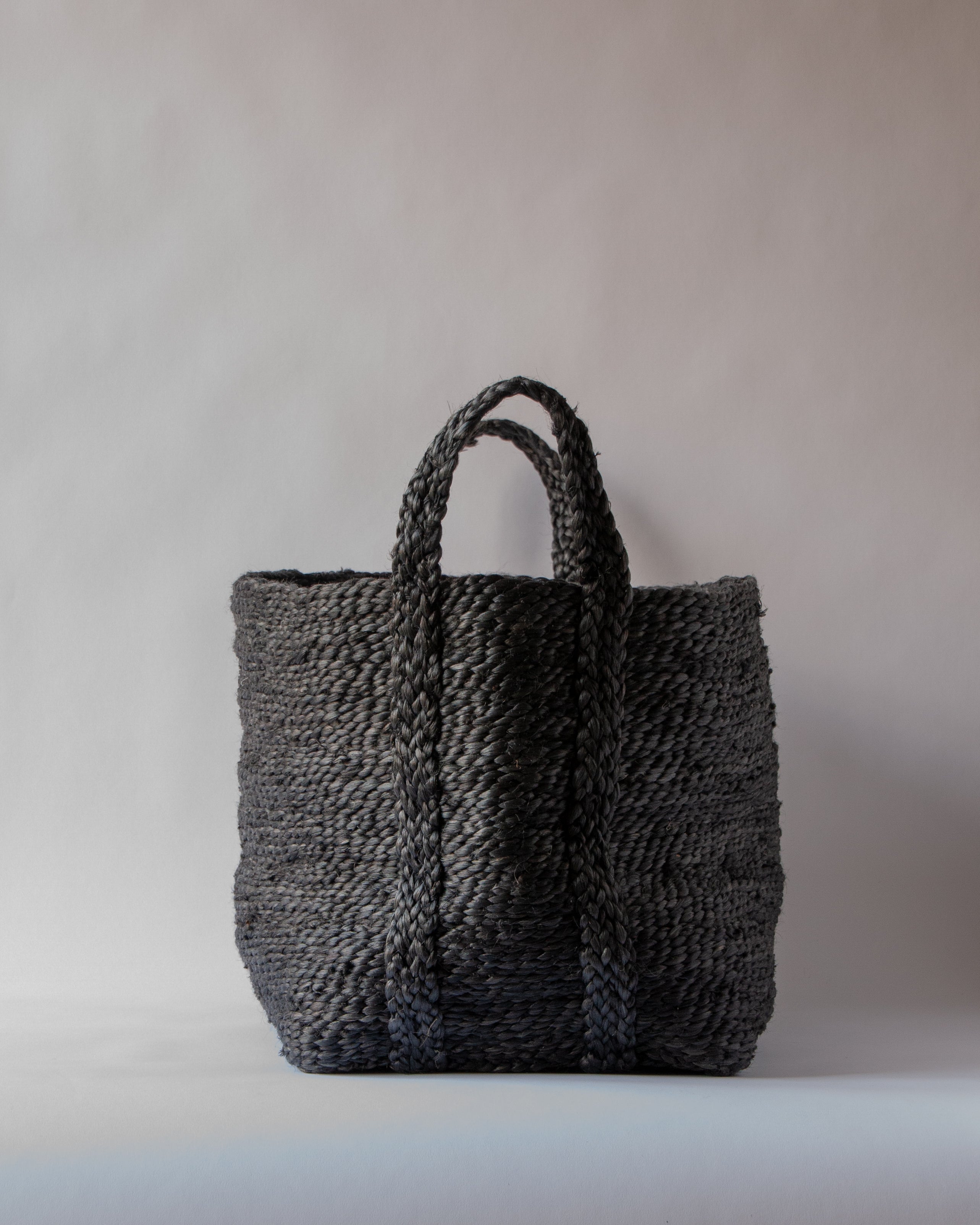 A gray Lucia jute basket with handles, woven from natural materials, displayed against a neutral background.